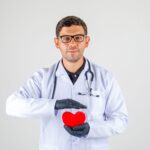 doctor-holding-heart-white-coat-with-stethoscope-looking-positive.jpg