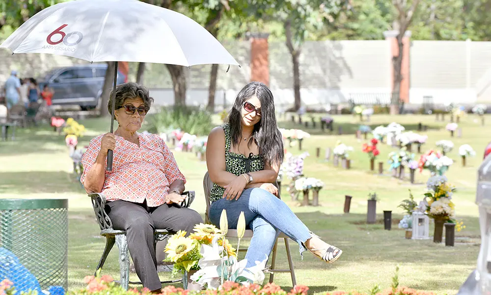 Dos mujeres colocando flores y velones