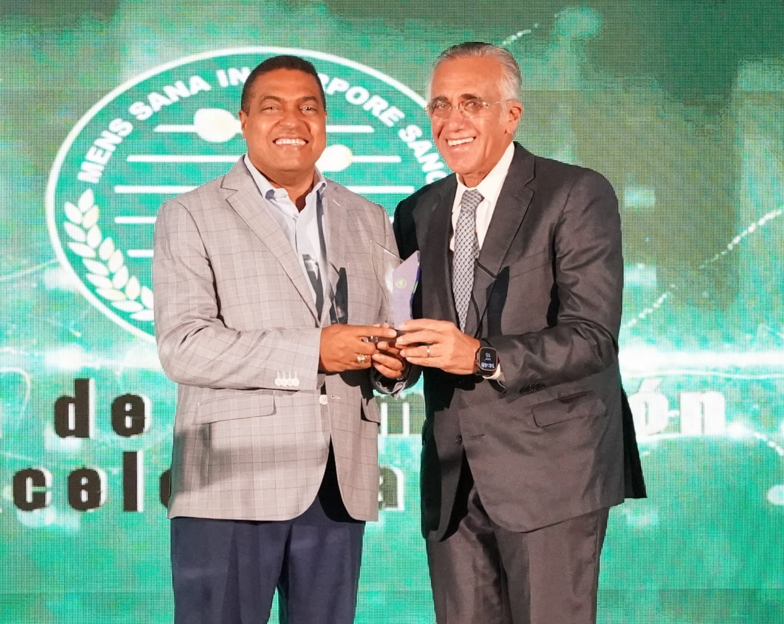 José P. Monegro recibe de manos de Luis Mejía un reconocimiento por su gestión como presidente del Comité Organizador de Santo Domingo 2026.